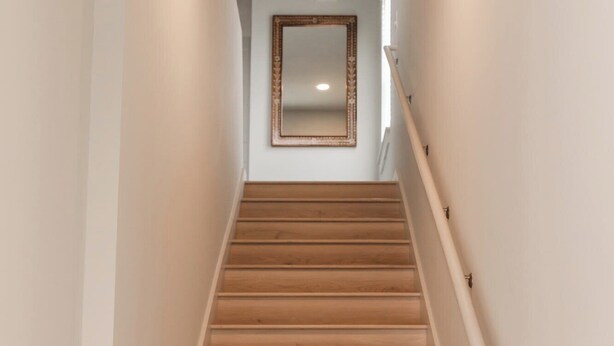 Una escalera con escalones de madera y una pared blanca.