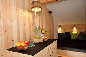 A wooden interior with a black countertop, a wooden cabinet, a bed with pillows, and a hanging light fixture. - "Tesitten" | ZumMoarSepp - Holiday apartment in the Villnöss Valley (Trentino-Alto Adige)