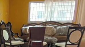 Een kamer met betegelde vloer, een bank en enkele stoelen.