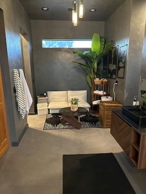 Eine moderne Küche mit einem weißen Sofa, einer großen Pflanze und einem Essbereich.
