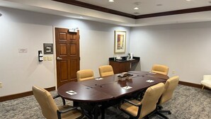 A conference room with a large table, six chairs, a door, a coat rack, and a framed picture on the wall. - Accessible 1BR Suite | Pool & Daily Breakfast (Oconomowoc)
