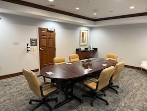 A conference room with a large table, six chairs, a door, a coat rack, and a framed picture on the wall. - Accessible 1BR Suite | Pool & Daily Breakfast (Oconomowoc)
