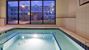 An indoor swimming pool with a view of a residential building through large windows. - Accessible 1BR Suite | Pool & Daily Breakfast (Oconomowoc)