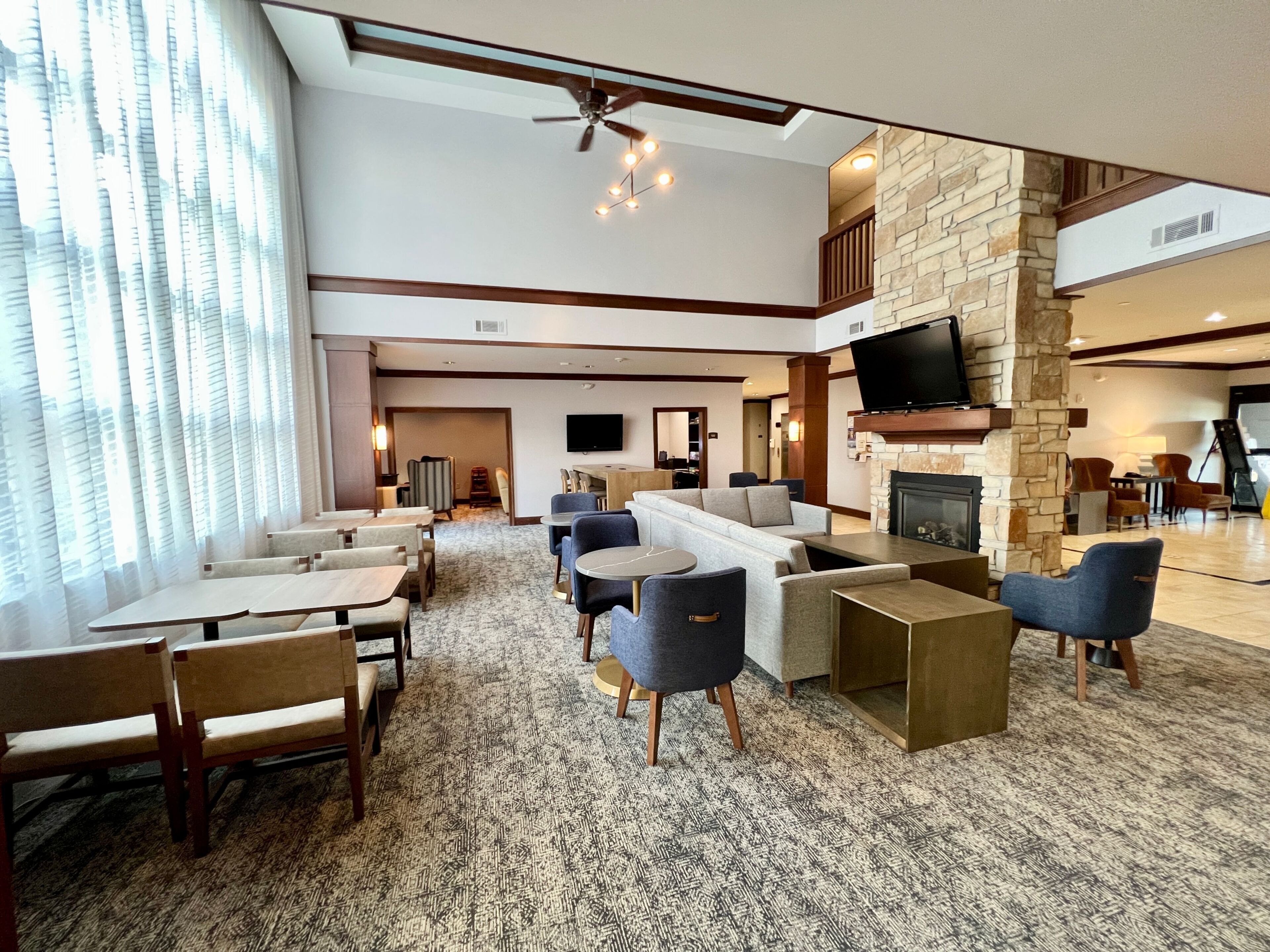 Et hotel lobby med siddeområde, pejs, fladskærm og trappe op til et højere niveau.