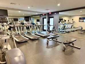 Un gimnasio con cintas de correr, elípticas y máquinas de pesas.