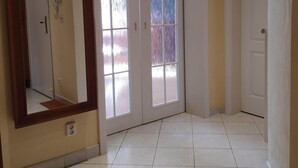 Un pasillo con un espejo grande, puertas dobles y piso de baldosas.