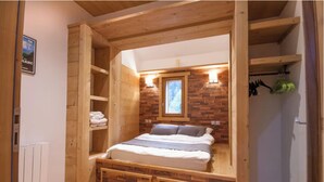 A wooden-framed bedroom with a bed, built-in shelves, a window, and a radiator. - Chalet-like triplex with separate entrance ideal for large families (Les Contamines-Montjoie)