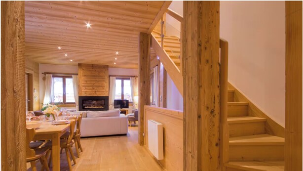 A wooden interior with a dining area, sofa, TV, fireplace, and wooden staircase. - Chalet-like triplex with separate entrance ideal for large families (Les Contamines-Montjoie)