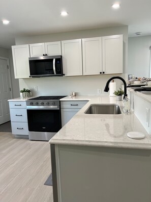 A modern kitchen with white cabinets, stainless steel appliances, and a marble countertop. - Harrison Place - Located on Evansville's Eastside (Evansville)