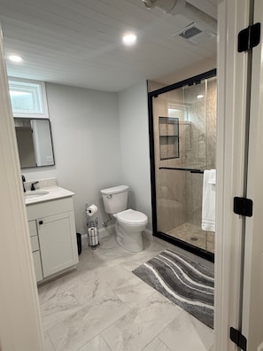 Et moderne badeværelse med toilet, vask og bruseniche.