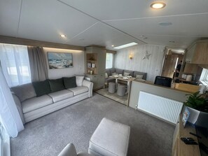 Ein modernes Wohnmobil-Interieur mit Sofa, Esstisch, Küchenzeile und einer Stern-Dekoration an der Wand.