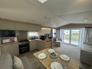Eine kompakte Küche mit modernen Geräten, ein Essbereich mit Tisch für vier Personen und ein Balkon mit Aussicht.