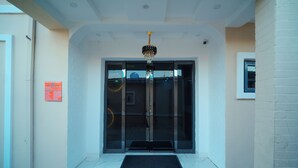 A hotel entrance with a glass door, a black mat, and a chandelier. - VHS VINCHEE SUITES II (Lagos)