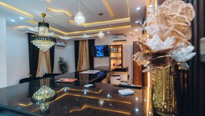 A modern hotel lobby with a reception desk, chandeliers, a television, and a plant. - VHS VINCHEE SUITES II (Lagos)