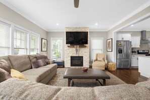 A living room with a stone fireplace, a flat-screen TV, a sofa, and a coffee table. - The Experience at ND<>4BR, 4BA <1 mi to ND Stadium (South Bend)