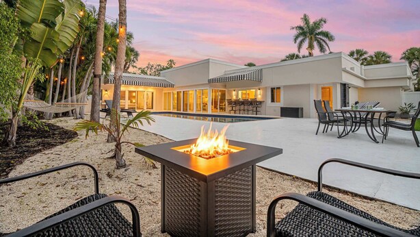 A modern outdoor patio with a square fire pit, seating, and a pool area. - St. Armands Circle Luxe 5BR Home with Private Pool (Sarasota)