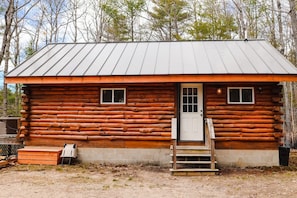 Eine Blockhütte mit Metalldach, einer Haustür und zwei Fenstern.