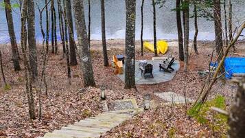 Une zone boisée avec une terrasse en bois menant à un terrain de camping situé au bord d’un lac.