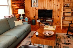 A cozy living room with a sofa, a television, a lamp, and a coffee table.