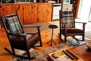 A cozy living room with a rocking chair, a small table, and a chair with a plaid blanket.