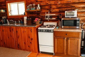 A kitchen with wooden cabinets, a stove, a microwave, and a sink.
