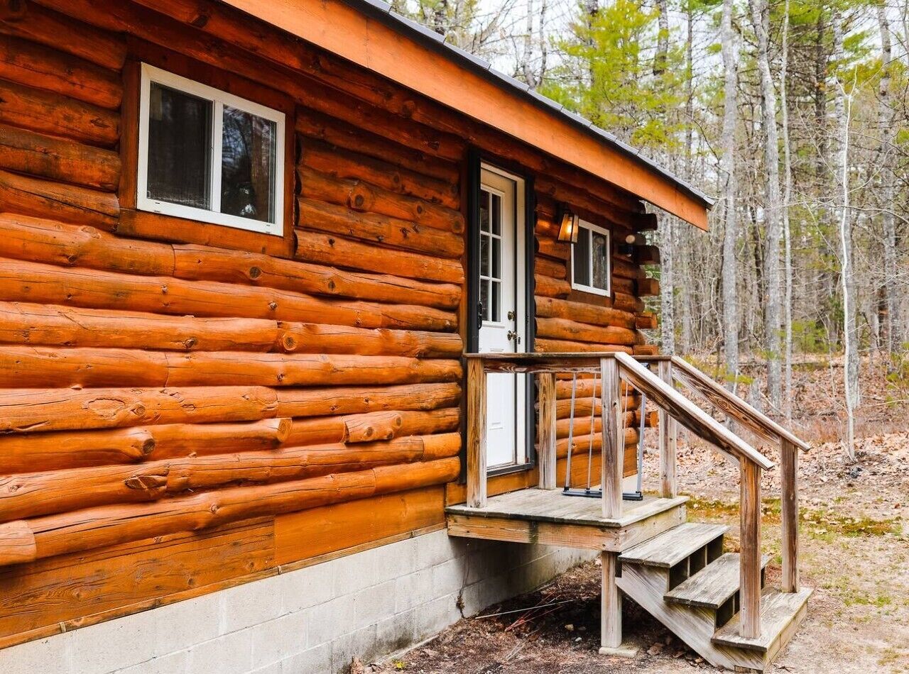 Une cabane en rondins avec un porche en bois et une porte.