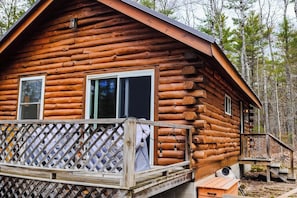 A log cabin with a deck and a small porch.