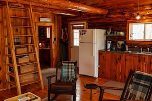 A cabin interior with a wooden interior, a refrigerator, a sink, and a chair. - Long Pond Cabin Retreat (Denmark)
