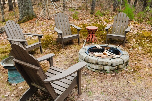 A campsite with Adirondack chairs and a stone fire pit.