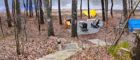 Un área boscosa con una terraza de madera que conduce a un camping junto a un lago.