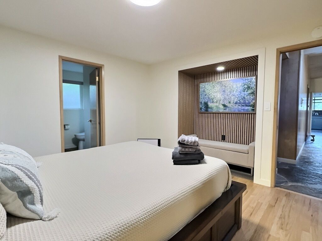 A bedroom with a bed, a window with a view, a door, and a small seating area.