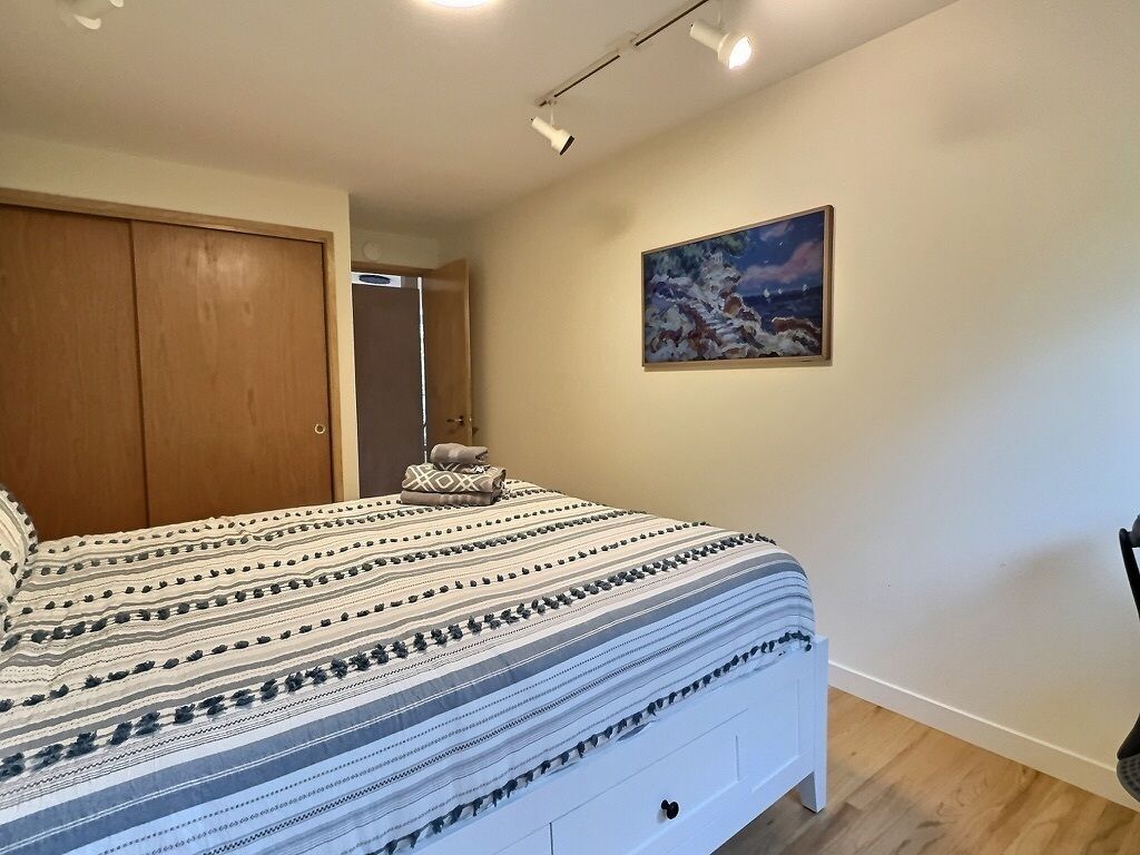 Ein Schlafzimmer mit einem Bett, einem Kleiderschrank, einem Bild und einer Tür.