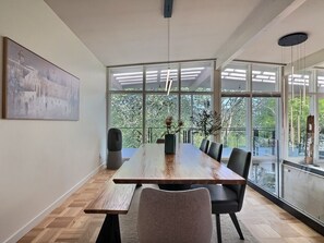 Ein Essbereich mit einem langen Holztisch, schwarzen Stühlen und einer Blumenvase.