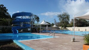 A swimming pool with a water slide, a covered seating area, and a pavilion. - Le Cocon Bleu - 2 steps from the beach 🌴✨ (Le Moule)