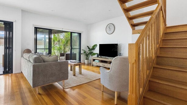 A modern living room with a sofa, armchair, coffee table, TV, and a staircase. - Seabrook – on Main Street, walk to beach & shops (Pottsville)