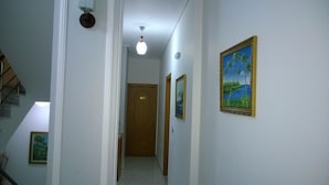 En hall med en dörr av trä märkt med siffran ’405’, en taklampa och två inramade tavlor på väggen.