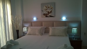 A neatly made bed with pillows, a wall-mounted artwork, and bedside lamps. - Hotel Ceko (Sarandë)
