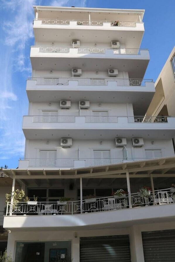 A multi-story building with balconies, air conditioning units, and a covered ground floor with outdoor seating. - Hotel Ceko (Sarandë)