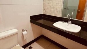 A bathroom with a toilet, sink, and mirror.