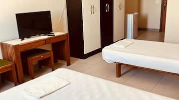 Una habitación de hotel con cama, escritorio con televisor, armario y refrigerador.