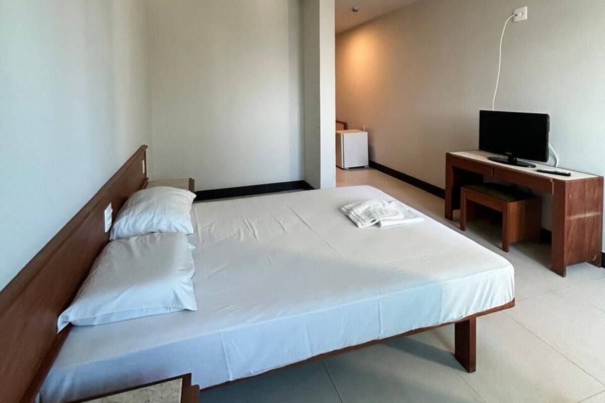 A hotel room with a bed, a desk, a television, and a lamp.