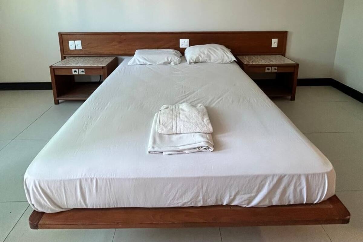 A single bed with a wooden headboard, a nightstand, and a folded towel on the bed.