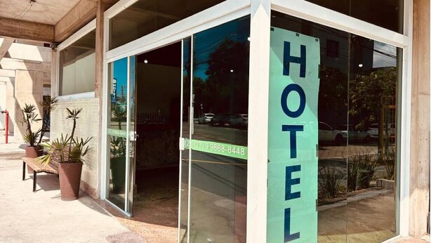 A hotel entrance with a glass door, a sign reading 'HOTEL', and a phone number.