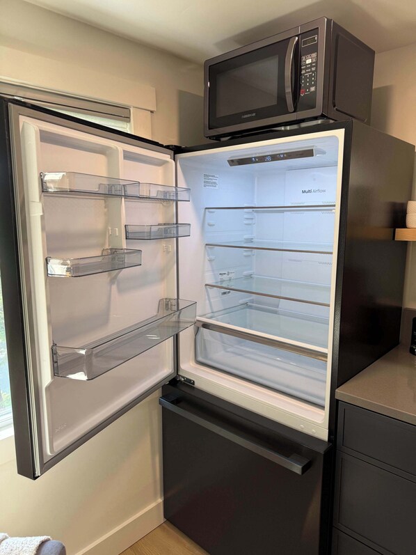A modern kitchen with a built-in microwave and a refrigerator with multiple shelves.