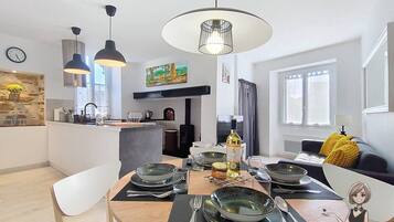 A modern kitchen with a dining area, featuring pendant lights, a central island, and a dining table set for a meal.