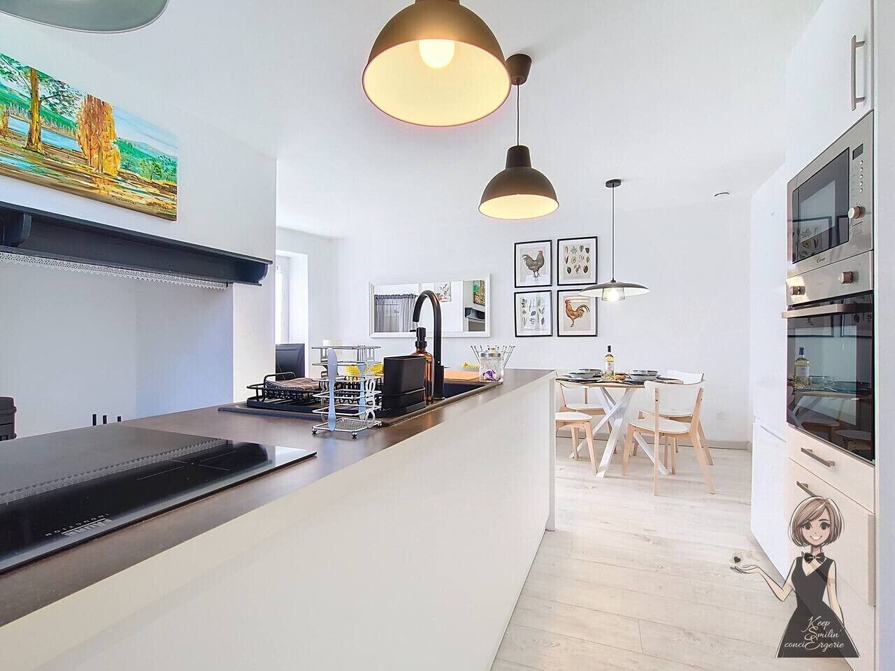 A modern kitchen with a central island, pendant lighting, and a dining area with chairs.