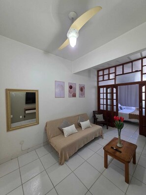 Ein Wohnzimmer mit Deckenventilator, einer Couch, einem Couchtisch und einem Bett mit Blick.