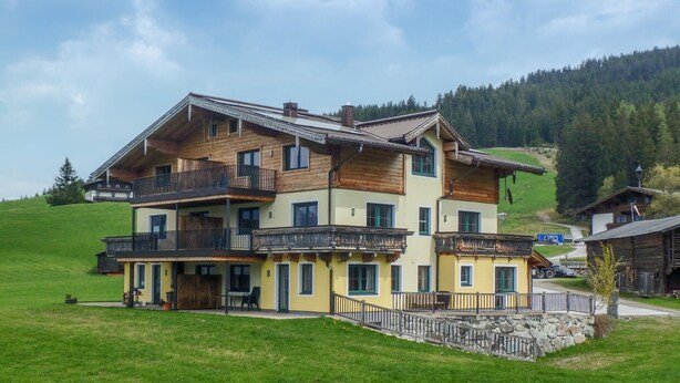A multi-story chalet with balconies, a stone foundation, and a hillside backdrop. - 3 bedroom awesome apartment in Hollersbach (Hollersbach)