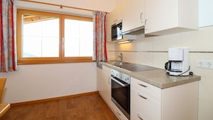 A compact kitchen with a window, a microwave, a coffee maker, and a stove. - 3 bedroom awesome apartment in Hollersbach (Hollersbach)
