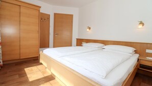Hotellihuone, jossa on parivuode, puinen vaatekaappi ja kaksi seinälle asennettua valaisinta.